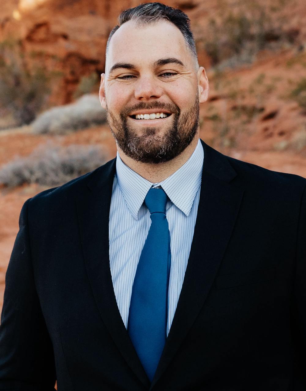 AJ Griffin, owner of Griffin Real Estate Team, in a dark suit against southern Utah red rock.