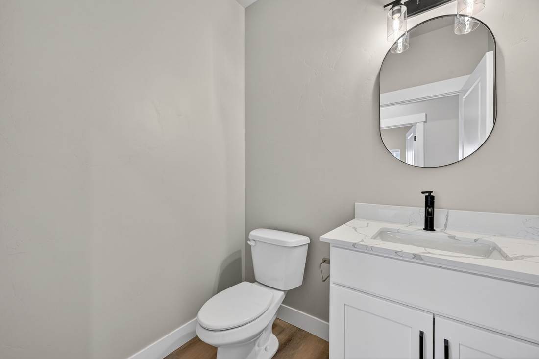 Powder bathroom with quartz-topped vanity, oval mirror, and a two-globe black vanity light.