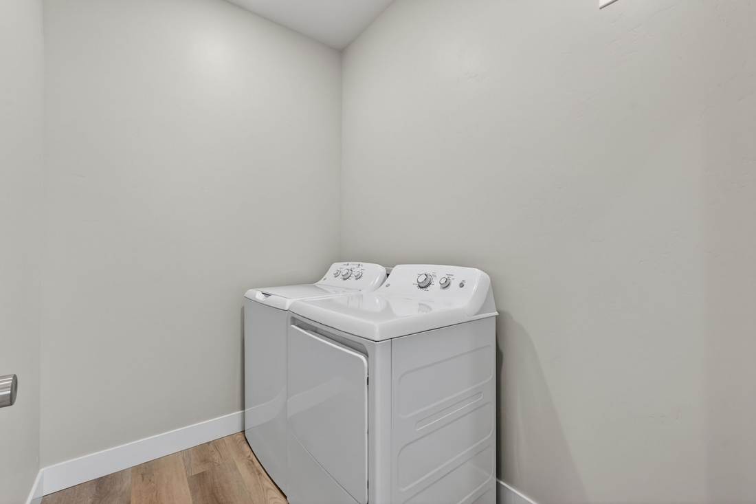 Dedicated laundry room with a white top-load washer and dryer already installed.