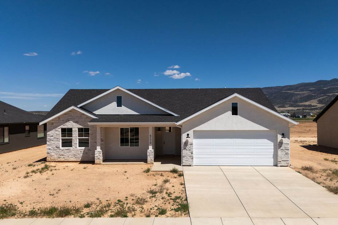 Front elevation of 5174 Sagewood with stone wainscot, gabled roof and white garage door.