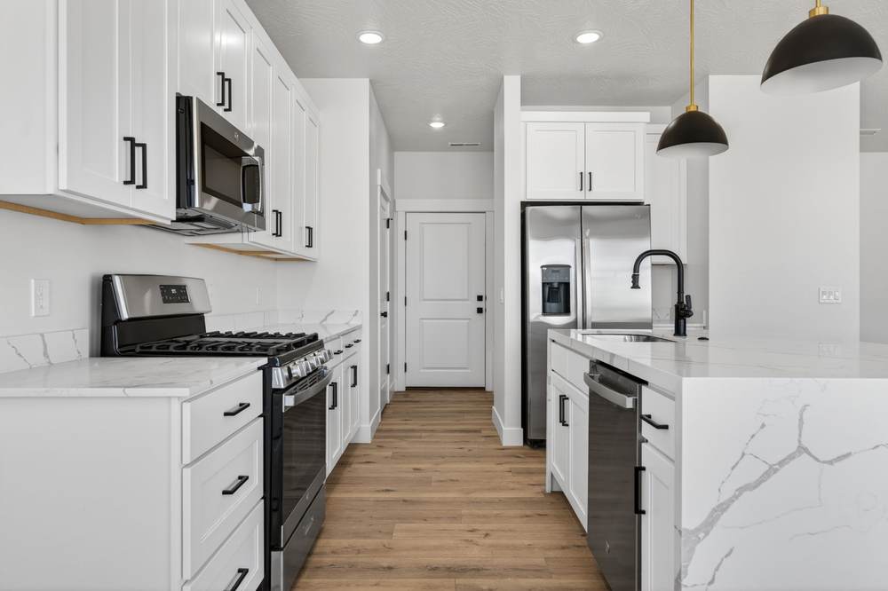 Galley run with stainless gas range, over-range microwave and quartz counters.