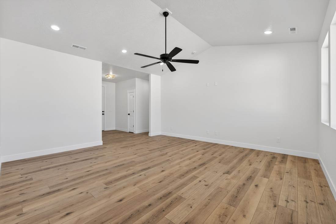 Great room with a vaulted ceiling, black ceiling fan and wide-plank luxury vinyl flooring.