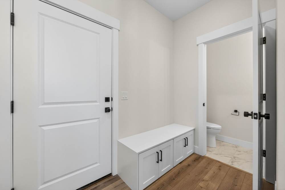 Mudroom with a built-in bench and cabinets, opening to a bathroom with marble-look tile.