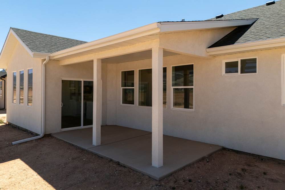 Covered rear patio on stucco columns off the back of the house.