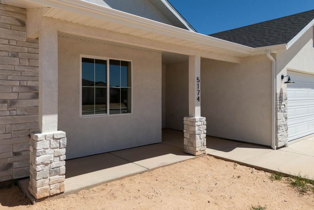 Covered front porch with stone columns and the house number 5174.